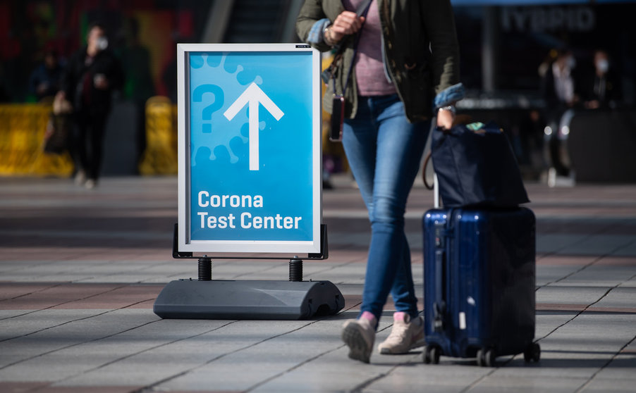26 March 2021, Bavaria, Munich: A woman passes past a sign with the inscription "Corona Test Center" at Munich airport. A new requirement for people arriving at German airports to have submitted to coronavirus testing has been postponed from Sunday to Tuesday. Photo: Sven Hoppe/dpa
