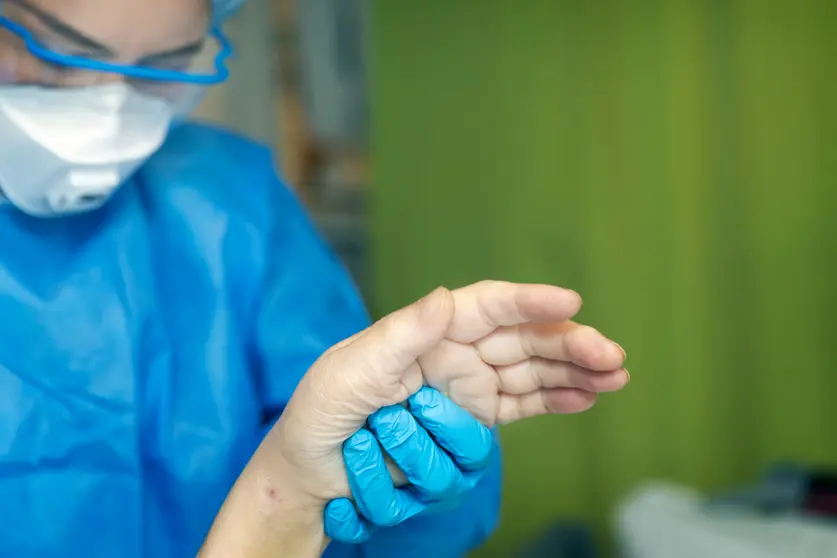 A Finnish medic holds the hand of a sick elderly person in the Helsinki hospital. Photo: @HUS.