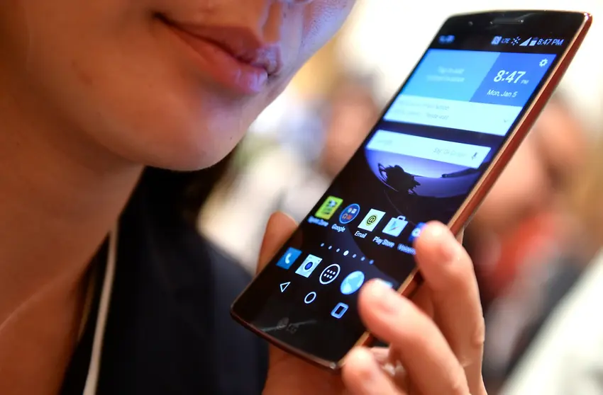 FILED - 05 January 2015, US, Las Vegas: A visitor holds an LG G Flex 2 smartphone at the consumer electronics show CES 2015. The South Korean electronics manufacturer LG is closing its loss-making mobile phone business. Photo: picture alliance / dpa