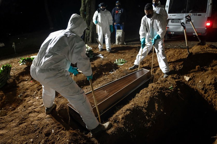 02 April 2021, Brazil, Sao Paulo: Employees of the Vila Formosa cemetery, the largest in Latin America, carry a coffin to bury a person who died of coronavirus (Covid-19). Due to the high number of deaths, the employees also work during the night. Photo: Lincon Zarbietti/dpa