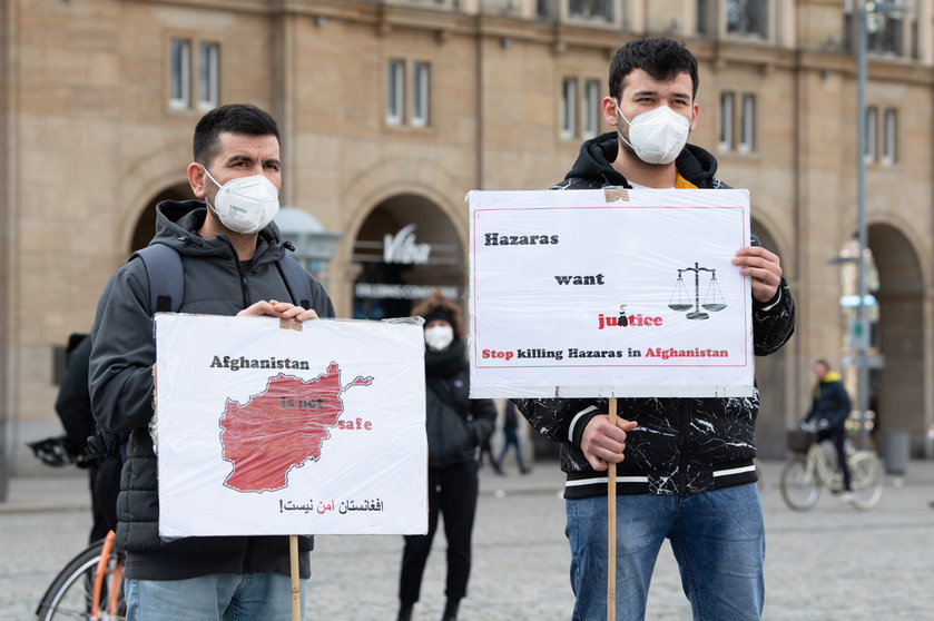 07 April 2021, Saxony, Dresden: Protesters hold signs during a rally called by the Dresden Afghanistan Association and the Saxon Refugee Council against collective deportations to Afghanistan on the Altmarkt. Photo: Sebastian Kahnert/dpa-Zentralbild/dpa