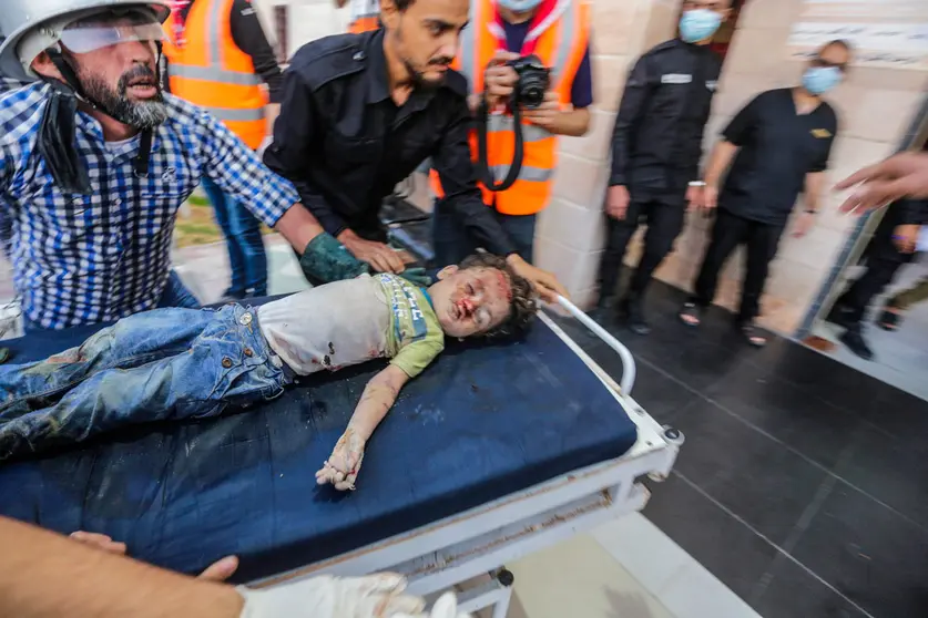 13 May 2021, Palestinian Territories, Gaza City: People transport the body of a Palestinian child who was killed after an Israeli airstrike on Gaza City to a hospital amid the escalating flare-up of Israeli-Palestinian violence. The Ministry of Health in the Gaza Strip said that at least 109 Palestinians, including 28 children, were killed in the recent Israeli airstrikes. Photo: Mahmoud Issa/Quds Net News via ZUMA Wire/dpa