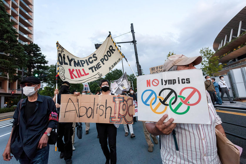 09 May 2021, Japan, Tokyo: Protesters hold up signs as they march in front of Tokyo's National Stadium, during a protest against hosting the 2020 Summer Olympics. Photo: Damon Coulter/SOPA Images via ZUMA Wire/dpa