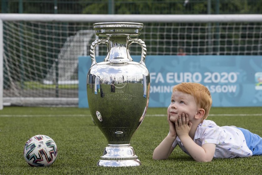 HANDOUT - 02 June 2021, United Kingdom, Glasgow: A handount pictures shows Glasgow youngster Hugo posing with the UEFA EURO 2020 Trophy as the Henri Delaunay Cup made a special visit to Glasgow on Wednesday as part of the UEFA EURO 2020 Trophy Tour. Photo: Jeff Holmes/JSHPIX via PA Wire/dpa - ATTENTION: editorial use only and only if the credit mentioned above is referenced in full
