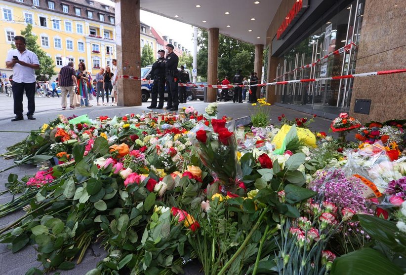 26 June 2021, Bavaria, Wuerzburg: Candles and flowers are placed in front of a closed and cordoned off department store in downtown Wuerzburg, where a fatal knife attack took place last night leaving three people dead and seven injured. Photo: Karl-Josef Hildenbrand/dpa
