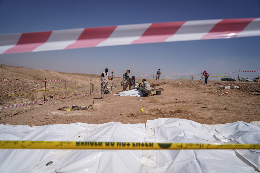 FILED - 13 June 2021, Iraq, Al-Humaydat: Members of expert teams take part in the opening of a mass grave and the exhumation of the remains of victims who were killed and buried by the so-called Islamic State (IS) terror group back in 2014. More than 500 people, predominantly Shia Muslims, where executed and buried in the mass grave during an IS attack on the Badush Prison on 10 June 2014. The mass grave, which was first discovered in 2017, is located in the village of Al-Humaydat, 30 km west of the city of Mosul, a former IS stronghold in Iraq's northern Nineveh Governorate. Photo: Ismael Adnan/dpa