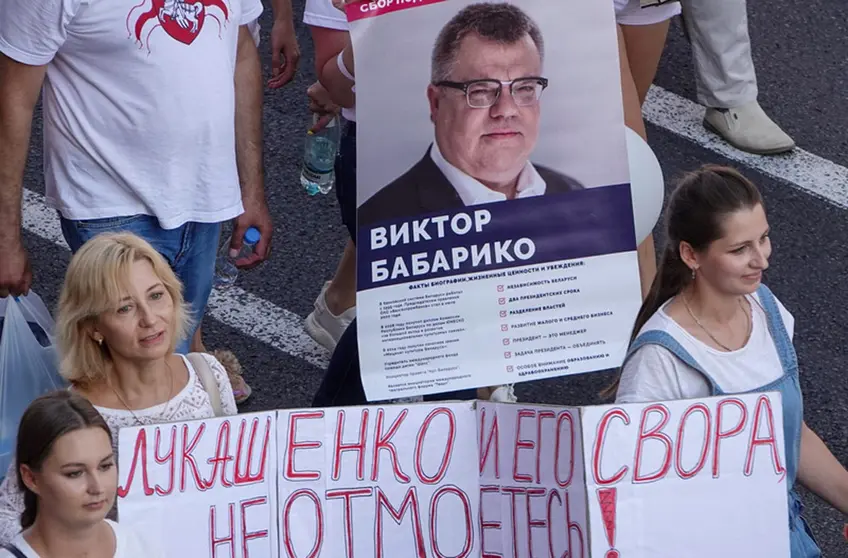 FILED - People walk in Minsk's Independence Square during a demonstration against Belarusian ruler Alexander Lukashenko, carrying a banner with the photo of Viktor Babariko, who wanted to run against Lukashenko in the presidential election. Photo: Ulf Mauder/dpa