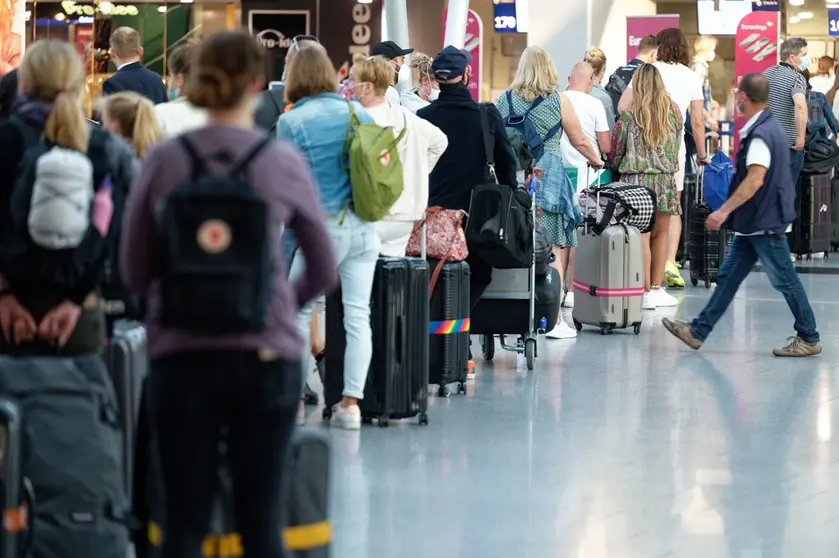 03 July 2021, North Rhine-Westphalia, Duesseldorf: Travelers wait in line to check in front of a counter at Duesseldorf airport. Photo: Henning Kaiser/dpa