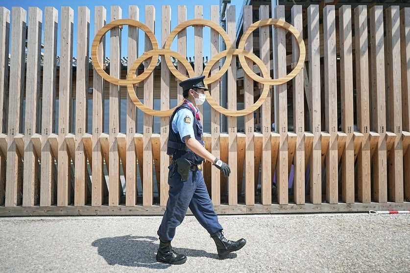 19 July 2021, Japan, Tokyo: A police officer walks past Olympic rings at the entrance to Olympic Village. The Olympic Village is a housing development that will house the participants of the 2020 Olympic Games. Tokyo 2020 Olympic Games will be held from 23 July to 8 August 2021. Photo: Michael Kappeler/dpa