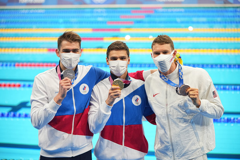 27 July 2021, Japan, Tokyo: (L-R) Russian Olympic Committee silver medallist Kliment Kolesnikov, Russian Olympic Committee gold medallist Evgeny Rylov, and US bronze medallist Ryan Murphy celebrate during the medal ceremony of the Men's 100m Backstroke Final swimming event at the Tokyo Aquatics Centre, during the Tokyo 2020 Olympic Games. Photo: Michael Kappeler/dpa