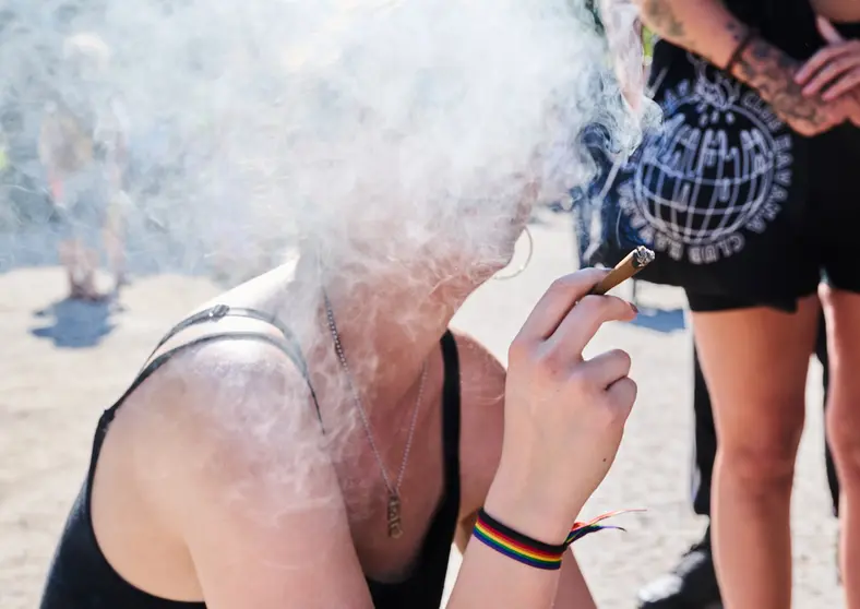 14 August 2021, Berlin: A demonstrator smokes a joint during the Hanfparade 2021 to call for legalizing cannabis use in Germany. Photo: Annette Riedl/dpa