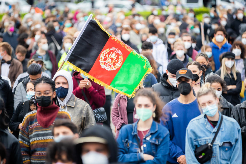 17 August 2021, Berlin: The flag of Afghanistan is held in front of the Reichstag building during a rally for a quick and unbureaucratic evacuation for threatened people from Afghanistan. Photo: Christoph Soeder/dpa