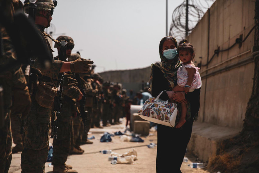 18 August 2021, Afghanistan, Kabul: 2 Marines from the 24th Expeditionary Unit (MEU) guide a woman carrying a child in her arms during an evacuation at Hamid Karzai International Airport in Kabul. US soldiers and Marines are assisting the State Department with an orderly withdrawal of designated personnel in Afghanistan. Photo: Nicholas Guevara/U.S. Marines via ZUMA Press Wire Service/dpa