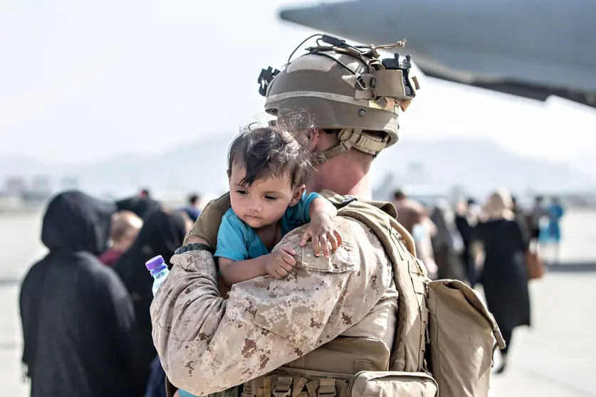 HANDOUT - 22 August 2021, Afghanistan, Kabul: A US marine soldier carries a young boy at the Hamid Karzai International Airport during the evacuation of civilians following the Taliban takeover. Photo: Sgt. Samuel Ruiz/U.S. Marine/Planet Pix via ZUMA Press Wire/dpa - ACHTUNG: Nur zur redaktionellen Verwendung und nur mit vollständiger Nennung des vorstehenden Credits