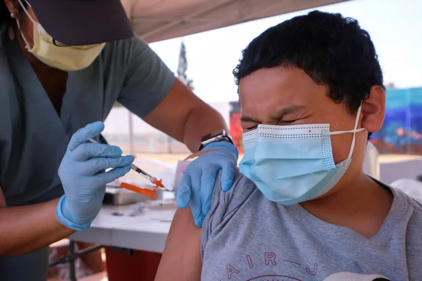 15 August 2021, US, Los Angeles: A boy receives a Coronavirus (Covid-19) vaccine dose during a free laptop giveaway event held by Spectrum and Los Angeles County Supervisor Hilda Solis in El Monte. Photo: Ringo Chiu/ZUMA Press Wire/dpa