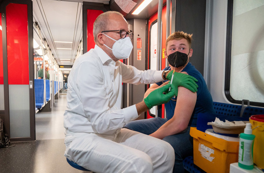 30 August 2021, Berlin: Christian Gravert, chief medical officer of the Deutsche Bahn, vaccinates a man in a special train of the S-Bahn, in which vaccinations with the vaccine of the manufacturer Johnson & Johnson are offered. Photo: Christophe Gateau/dpa