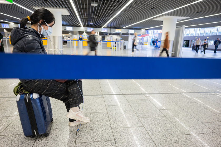 FILED - A tourist sits on her suitcase and waits for a return flight to her home country from Frankfurt. A US entry ban for Europe - now set to fall away for those who are vaccinated against Covid-19 - has disrupted travel the last two years. Photo: Andreas Arnold/dpa