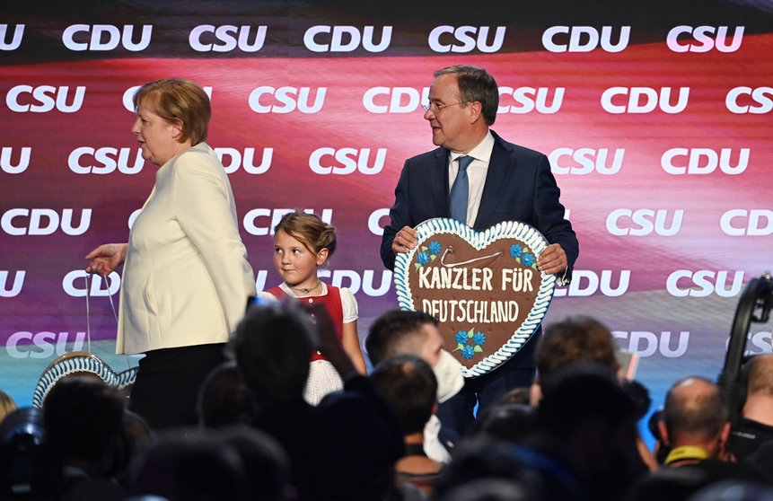 24 September 2021, Bavaria, Munich: Armin Laschet , candidate for Chancellor of the CDU/CSU party and Prime Minister of North Rhine-Westphalia, and Chancellor Angela Merkel (CDU) are on stage at the official end of the election campaign of the CDU and CSU in the Festhalle at the Nockherberg. Laschet is holding a gingerbread heart with the sugar icing inscription "Chancellor for Germany". Photo: Matthias Balk/dpa