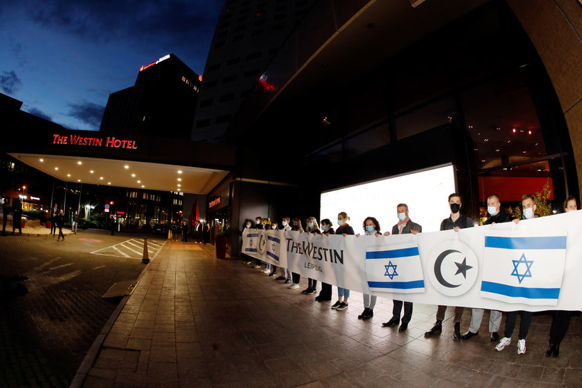 05 October 2021, Saxony, Leipzig: Employees of the Westin Hotel who want to set a sign against anti-Semitism with a banner. Following allegations of anti-Semitism, hundreds of people gathered in front of the "Westin Hotel" Leipzig this evening to show solidarity with the musician Gil Ofarim and Jews in Germany. Ofarim had been the victim of an anti-Semitic incident at the Leipzig hotel on Monday, according to his own account. An employee of the "Westin Leipzig" had asked him at the reception to pack his Star of David. Photo: Dirk Knofe/dpa.