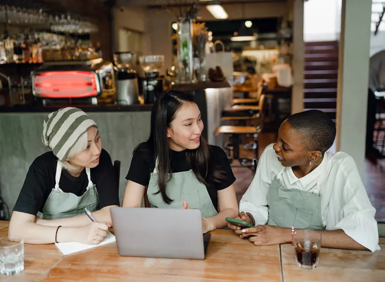 Women employees of a cafeteria, in front of a laptop. Photo: Pexels.