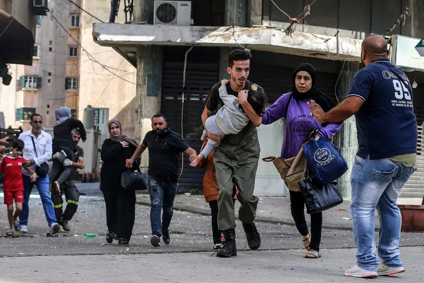 Civilians run for cover after gunfire erupted at a protest by supporters of the Shiite Hezbollah movement against the judge investigating the city's port port blast, near the former civil war front-line between Muslim Shiite and Christian areas. At least six people were killed and 30 injured in Beirut as gunfire broke out at a protest against the judge investigating last year's blast at the city's port, the Lebanese Red Cross said. Photo: Marwan Naamani/dpa.