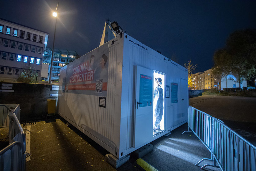 08 November 2021, Hessen, Frankfurt/Main: An employee of a Coronavirus test centre stands in the open door to the container in which the test cabins are housed. Photo: Boris Roessler/dpa