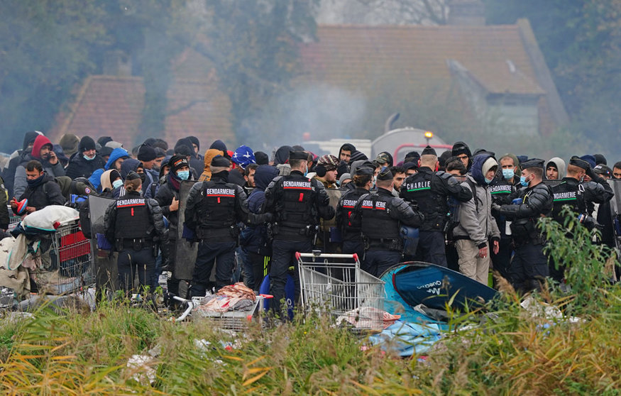 16 November 2021, France, Dunkirk: Migrants wait at a makeshift camp on the site of a former industrial complex in Grande-Synthe, as French police are evacuating migrants from the site, where at least 1,500 people had gathered in hopes of making it across the English Channel to Britain. Photo: Gareth Fuller/PA Wire/dpa.