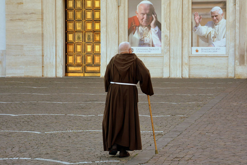 A friar walks towards the church leaning on a cane. Photo: Pixabay.