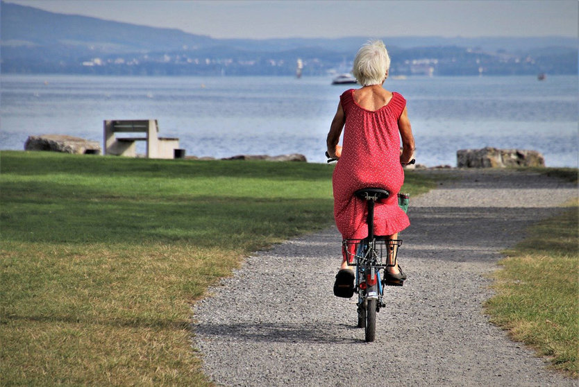 An older lady rides a bicycle. Photo: Pixabay.