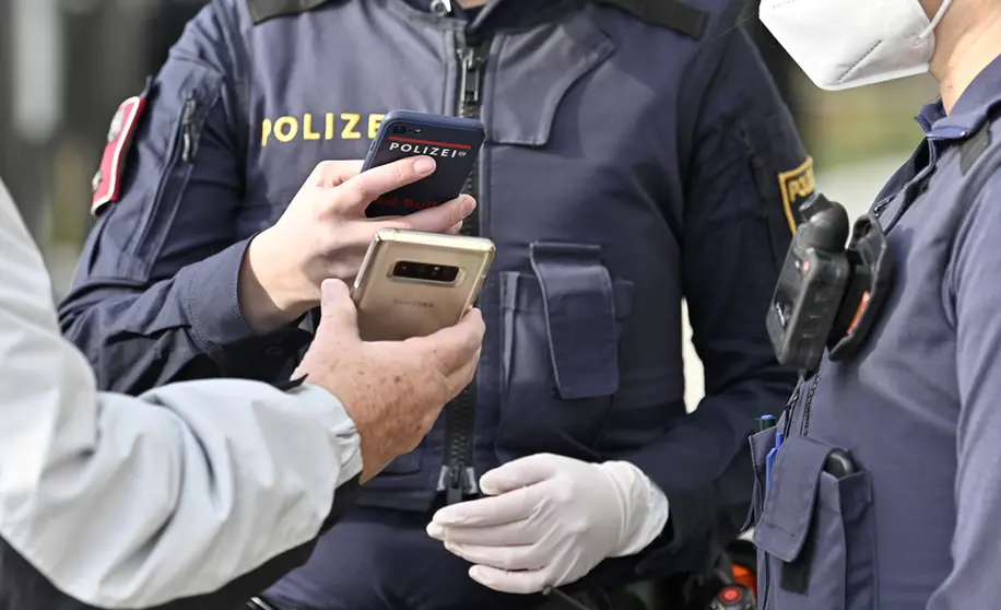 16 November 2021, Austria, Voesendorf: A policeman checks the covid passport of a citizen amid lockdown imposed by the authorities on unvaccinated people. Photo: Hans Punz/APA/dpa.