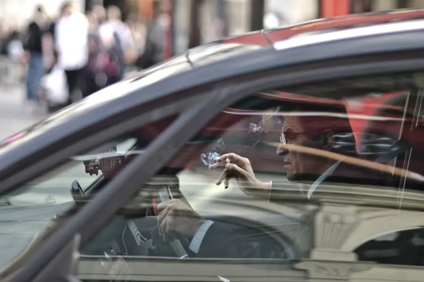 A driver smokes a cigarette while driving his private car. Photo: Pixabay.