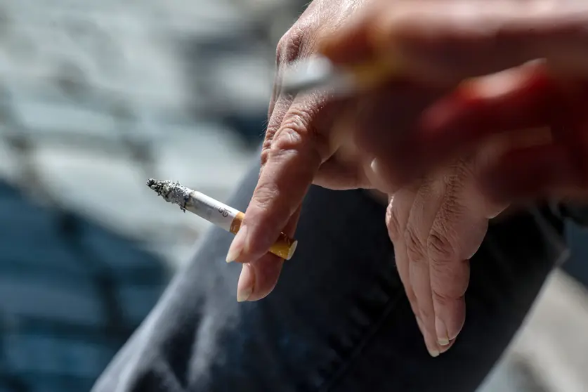 FILED - A smoker holds a burning cigarette in her hand. For three years, the association "Amberger Kippenjäger" has been campaigning for a clean city and for clean groundwater. The initiative collects cigarette butts so that they can be taken for recycling and do not end up in the residual waste. Photo: Armin Weigel/dpa.