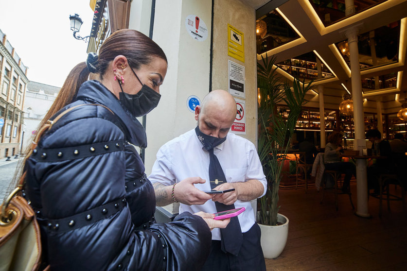 20 December 2021, Spain, Sevilla: Customers show a waiter their Corona certificates before entering a bar in Sevilla. Starting on Monday, only customers who are vaccinated, recovered or have a negative test result will be allowed into bars, restaurants, and hotels in Andalusia. Photo: Joaquin Corchero/EUROPA PRESS/dpa