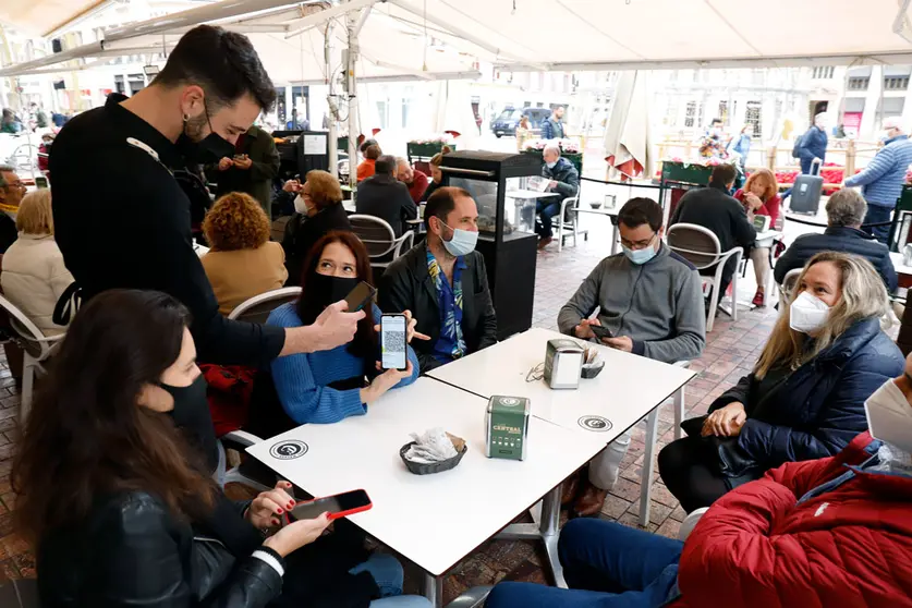 20 December 2021, Spain, Malaga: A woman shows her Corona certificate to a waiter at a bar in Malaga. Starting on Monday, only customers who are vaccinated, recovered or have a negative test result will be allowed into bars, restaurants, and hotels in Andalusia. Photo: Álex Zea/EUROPA PRESS/dpa.