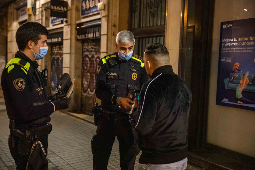 24 December 2021, Spain, Barcelona: Police officers fine a person after checking his papers and reasons to be outside during curfew time that was imposed as part of coronavirus measures. Photo: Kike Rincón/EUROPA PRESS/dpa.