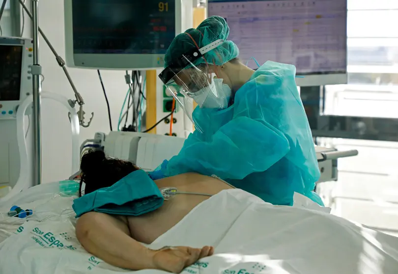 27 December 2021, Spain, Palma: A nurse cares for a patient in the intensive care unit of the main hospital Son Espases for coronavirus patients. Photo: Clara Margais/dpa.