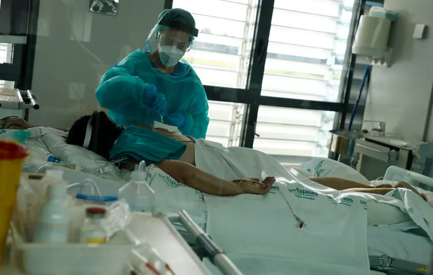 27 December 2021, Spain, Palma: A nurse cares for a patient in the intensive care unit of the main hospital Son Espases for coronavirus patients. Photo: Clara Margais/dpa.