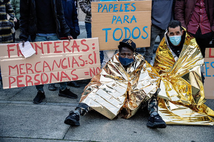 18 December 2021, Spain, Madrid: Demonstrators sit on the ground during a rally in the Plaza Juan Goytisolo on the occasion of Migrants Day. Photo: Carlos Luján/EUROPA PRESS/dpa.
