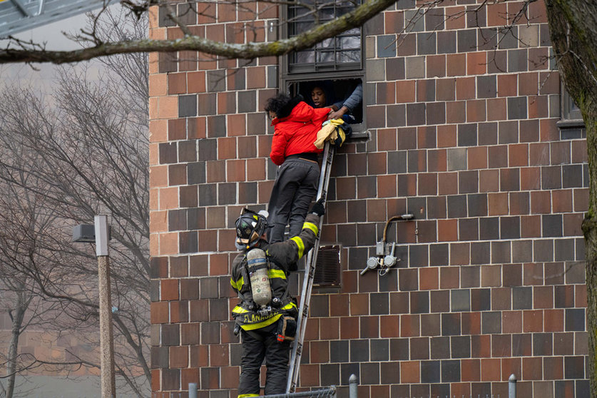 09 January 2022, US, New York: A firefighter hoists a ladder to rescue people through their windows after a fire broke out inside a third-floor duplex apartment in a Bronx apartment building, left at Least 19 Dead, Including 9 Children. Photo: Theodore Parisienne/New York Daily News/dpa.