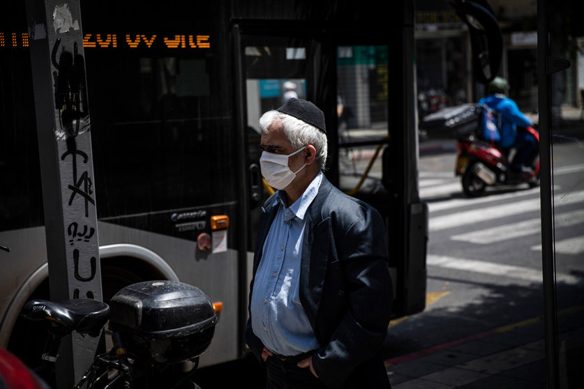 FILED - 20 April 2020, Israel, Tel Aviv: A man wearing a face mask walks on a street near a public bus. The number of serious Covid-19 cases in Israel continues to rise to record highs, with 1,263 reported on Sunday. Photo: Ilia Yefimovich/dpa.