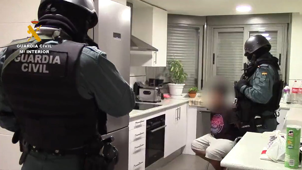 10/02/2022 Civil Guard officers carrying out the search of a home in the presence of one of the detained persons. Image: video screenshot by Guardia Civil.