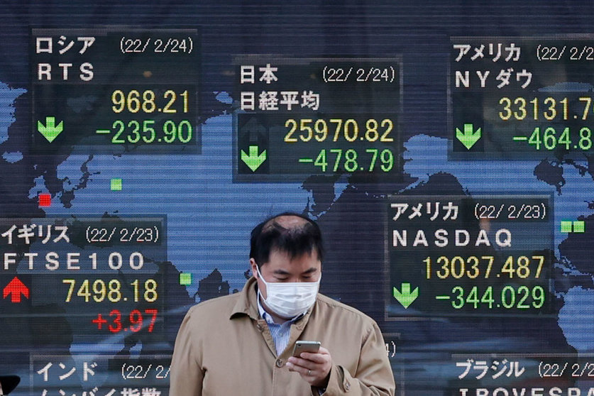 24 February 2022, Japan, Tokyo: A man walks past an electronic stock exchange board displaying Japan's Nikkei stock index in downtown Tokyo. Japan's Nikkei index fell below 26,000 points on Thursday for the first time since November 2020 after Russian troops attacked Ukraine in the morning. Photo: Rodrigo Reyes Marin/ZUMA Press Wire/dpa.