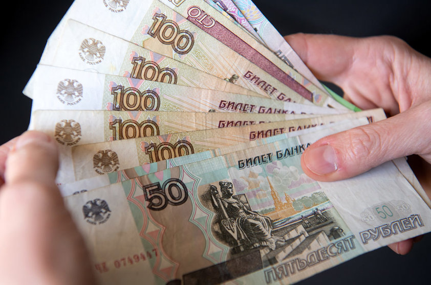 28 February 2022, Bavaria, Munich: A woman holds Russian ruble banknotes in her hands. The European Union put its severe sanctions against the Russian Central Bank into effect on Monday night. Photo: Sven Hoppe/dpa.