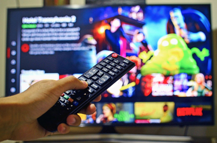 A Netflix user with the TV remote. Photo: Pixabay.