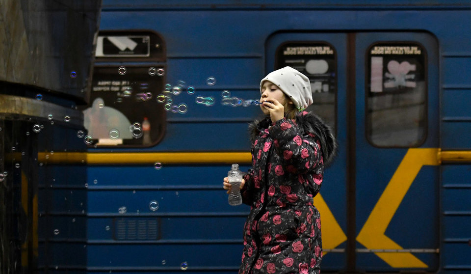 26 March 2022, Ukraine, Kiev: A young girl blows bubbles as people take shelter in a metro station serving as an underground bomb shelter. Photo: Carol Guzy/ZUMA Press Wire/dpa.