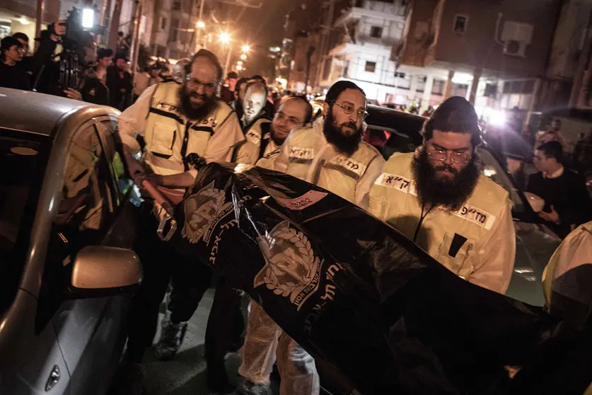 29 March 2022, Israel, Bnei Brak: Medics transport a body following a shooting attack. A man riding a motorcycle reportedly opened fire on passers-by in the city of Bnei Brak near Tel Aviv killing at least four people in the third incident of its kind within a week. Photo: Ilia Yefimovich/dpa - ATTENTION: graphic content.