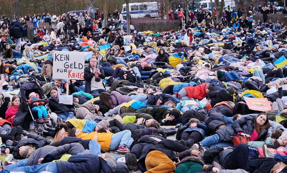06 April 2022, Berlin: Demonstrators lie on the lawn in front of the Reichstag building during a demonstration against the attack on Ukraine and for an energy embargo against Russia. Photo: Annette Riedl/dpa.