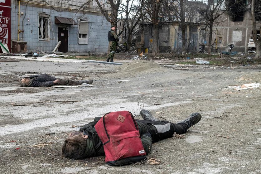 03 April 2022, Ukraine, Mariupol: The bodies of a civilians lay in an intersection in the centre of Mariupol as a Donetsk People's Republic fighter stands guard. Photo: Maximilian Clarke/SOPA Images via ZUMA Press Wire/dpa - ACHTUNG: Graphic Content.