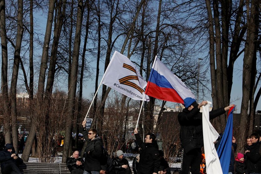 18 March 2022, Russia, Moscow: People hold flags on the sidelines of a concert held to mark the eighth anniversary of Russia's annexation of Crimea. Photo: Str/dpa.