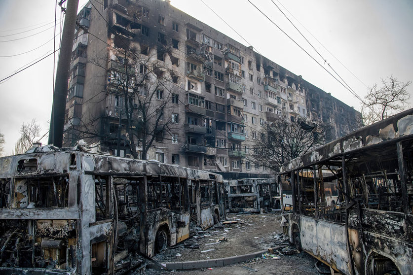 23 March 2022, Ukraine, Mariupol: Burned buses are seen in front of a destroyed residential complex in the besieged Ukrainian city of Mariupol. Photo: Maximilian Clarke/SOPA Images via ZUMA Press Wire/dpa.